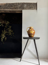 Decorative vase on a small table in front of a black fireplace.