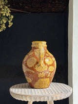 Decorative vase with floral patterns on a small round table against a dark background