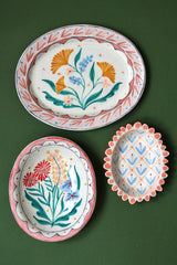 Three ceramic dishes with floral and geometric patterns on a green background