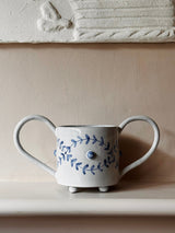Ceramic mug with floral design and handle on a neutral background
