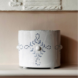 White ceramic pot with decorative blue patterns on a beige surface