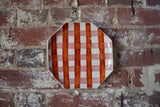 Hexagonal plate with red and white checkered pattern on a brick wall
