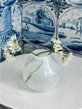 Clear glass vase with white flowers against a decorative blue and white tile background