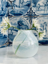 Clear glass vase with white flowers against a blue and white tiled wall