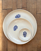 Set of white ceramic plates with blue floral designs on a wooden floor.