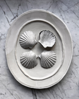 Decorative stone ring with four shell-shaped stones on a marble surface