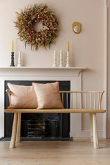 Nestled living room with a wooden bench, floral wreath, and candles.