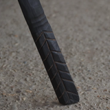Close-up of a black metal rod with textured surface on a concrete floor.