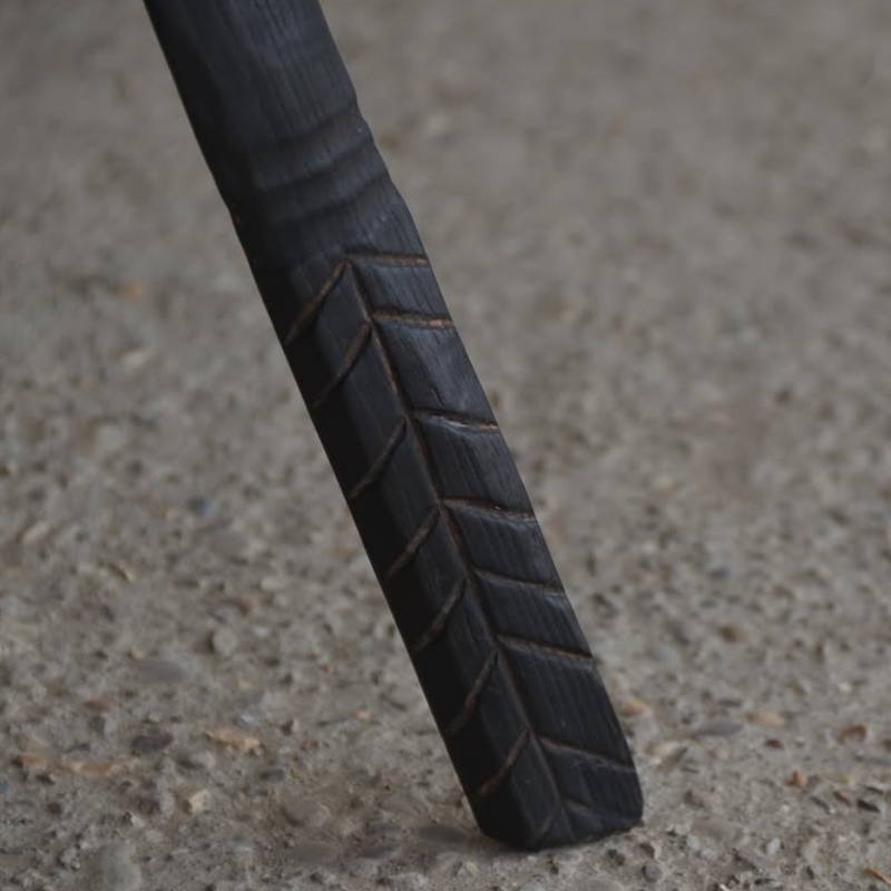 Close-up of a black metal rod with textured surface on a concrete floor.