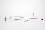 A minimalist black metal wire sculpture on a solid white background.