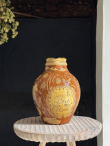 Decorative ceramic vase with text on a small round table against a dark background