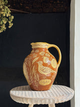 Decorative ceramic pitcher with floral and skylark design on a dark background