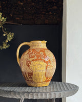 Decorative ceramic pitcher with intricate designs on a textured surface.