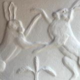 Relief sculpture of two figures in a dynamic pose on a plain background