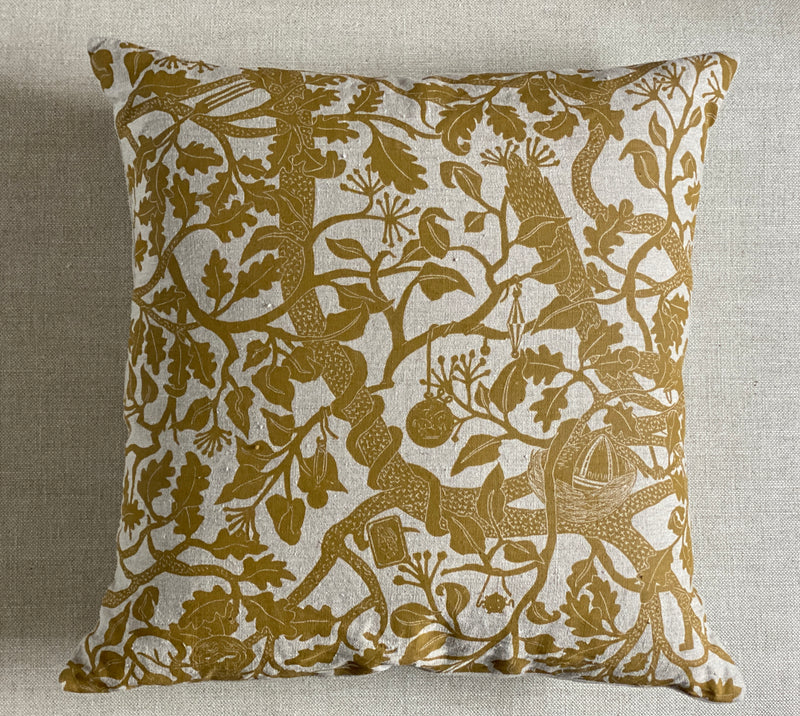 Decorative pillow with gold animal and floral pattern on a neutral background