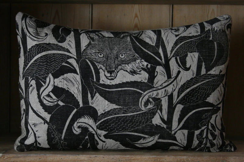 Decorative pillow with fox and leaf pattern on a wooden background