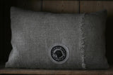 Gray pillow with a logo on a wooden surface