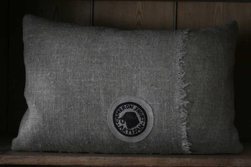 Gray pillow with a logo on a wooden surface