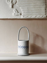White ceramic basket with blue pattern on a beige surface