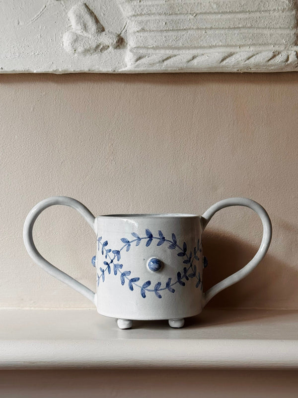 Ceramic mug with floral design and handle on a neutral background