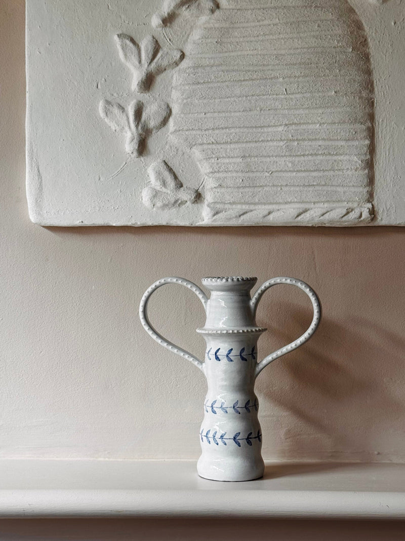 White ceramic vase with handles on a neutral background