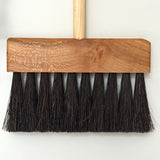 Wooden push broom with black bristles on a white background
