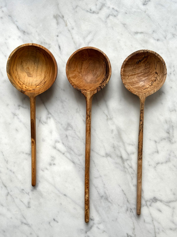 Three wooden ladles on a marble surface