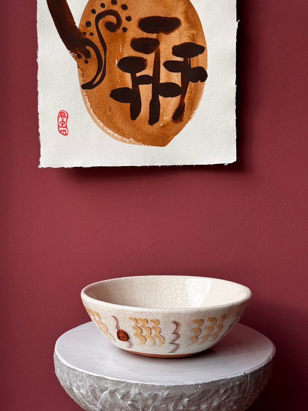 Ceramic bowl on a stone surface with a piece of paper featuring Japanese characters on a red wall.