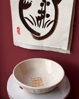 Ceramic bowl with floral design on a white surface against a maroon background