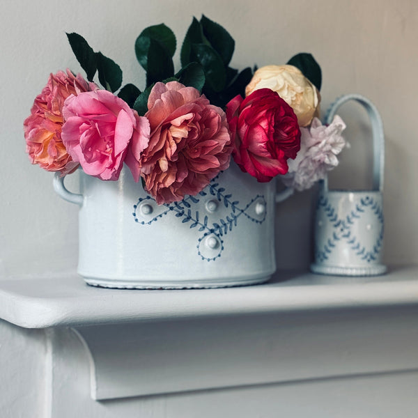 Decorative white bucket with floral arrangement on a shelf