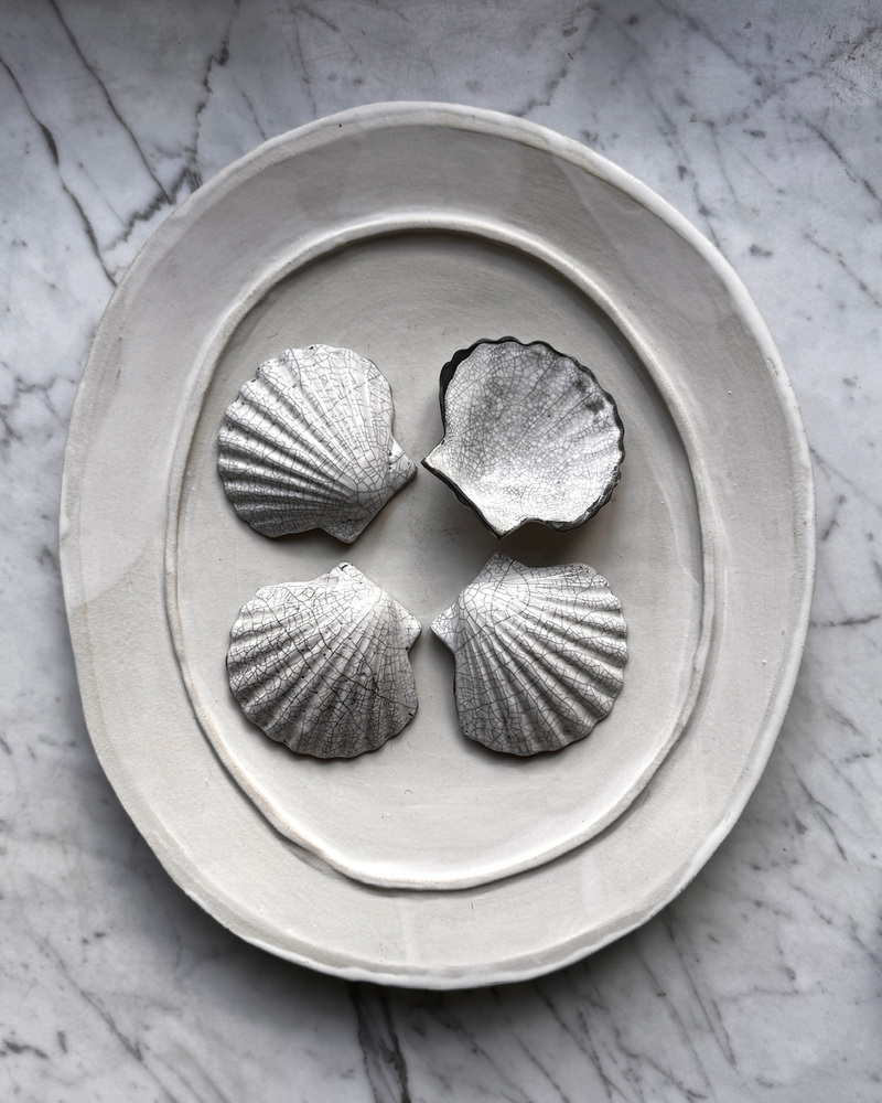 Decorative stone ring with four shell-shaped stones on a marble surface