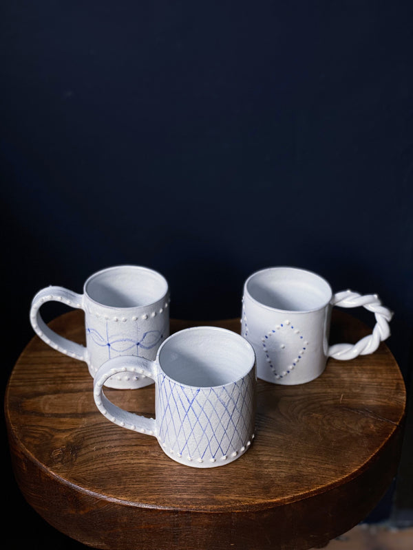 3 white ceramic mugs  by Emily Mitchell with painted blue decoration
